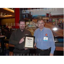 Standing in front of their Boardwalk backdrop at the ASI show, Dave Logan (right) and Jeff Karn (left) accept the Play Meter Operator's Choice Award for Merit.